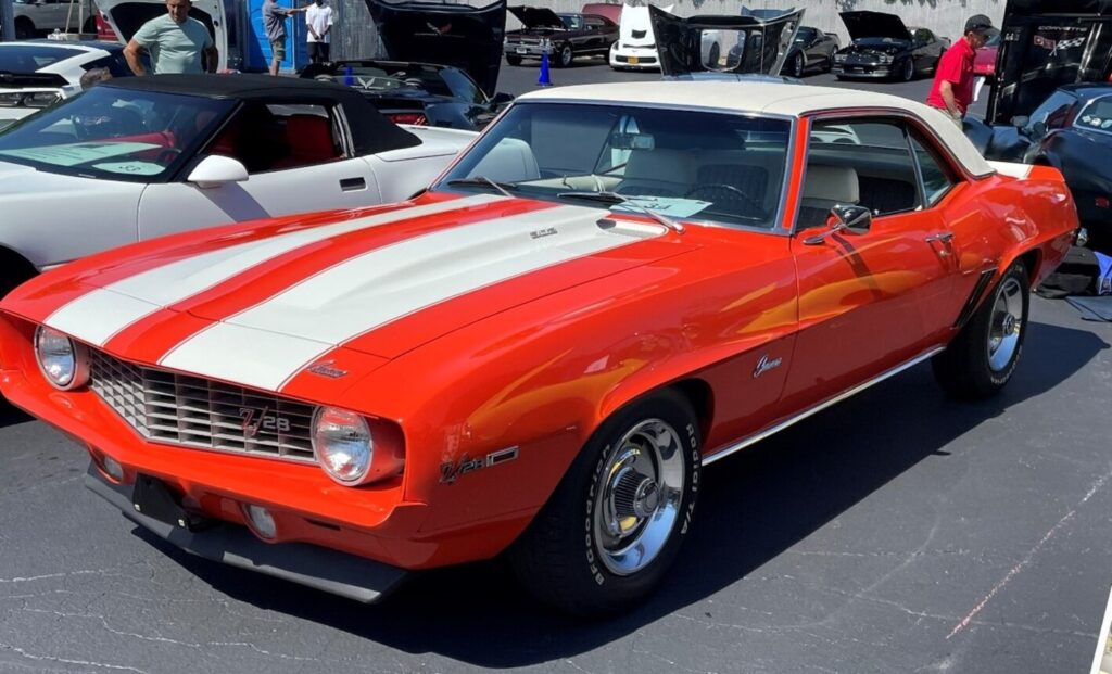 An orange with while stripes and white vinyl top 1969 Chevrolet Camaro at a car show