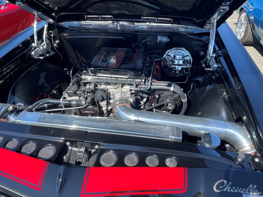 A supercharged Chevy LS engine in a 1969 black with red stripes Chevelle with load of modern tech