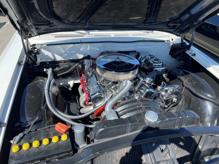 A small block Chevy engine in a white car with loads of chrome and modern tech