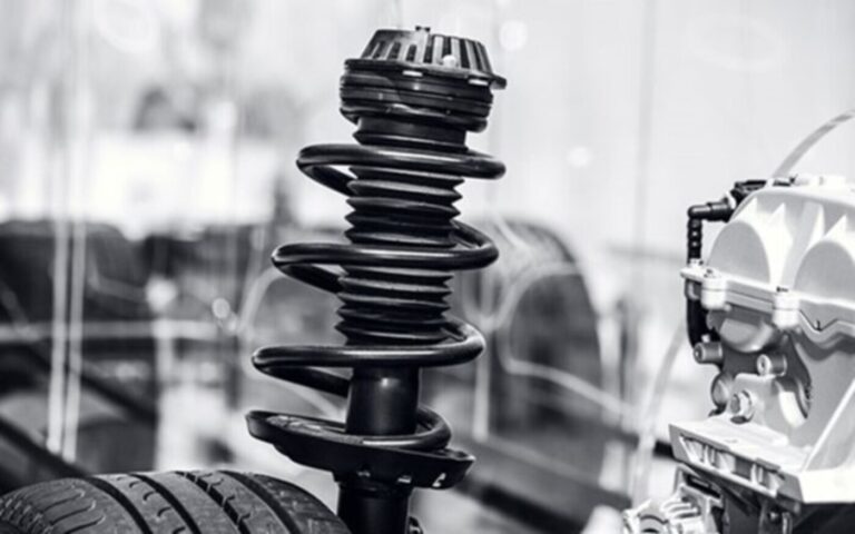 A black and while photo of a coil spring installed over a car strut