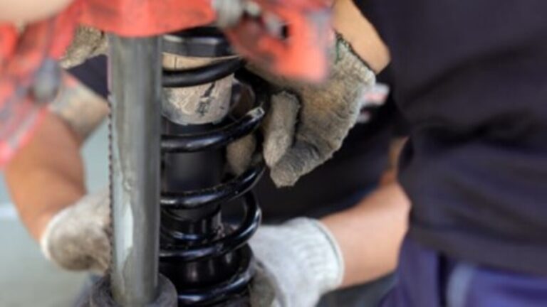 A mechanic installing a black coil spring over a strut