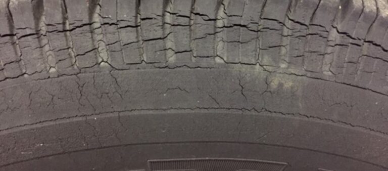 The sidewall of a car tire filled with cracks noting the car tire dry rot