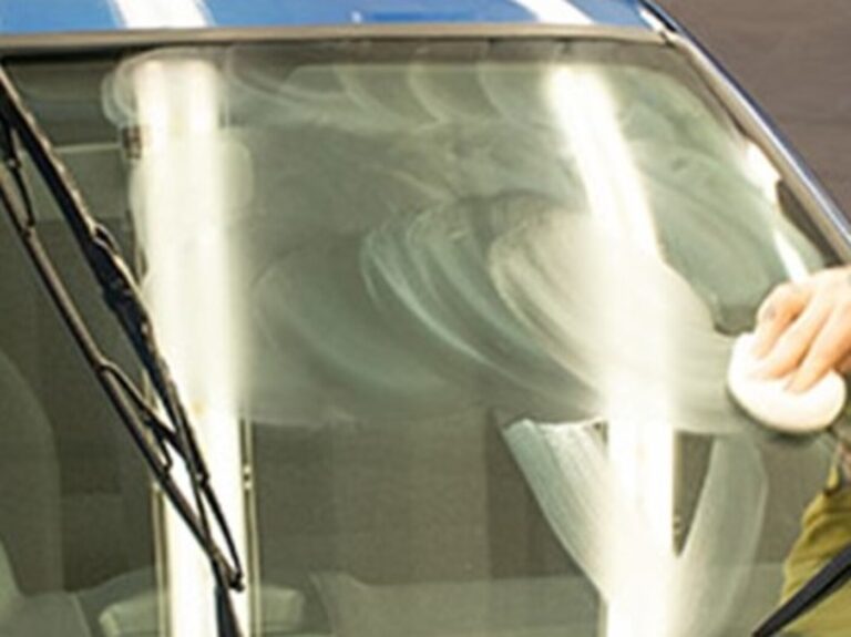 A detailer using a clay-bar on a windshield to get spotless car glass