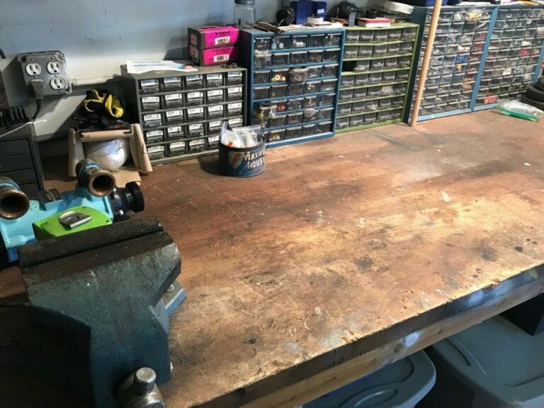 A wood work bench, with hardware bins and a vise in preparation for putting parts back together