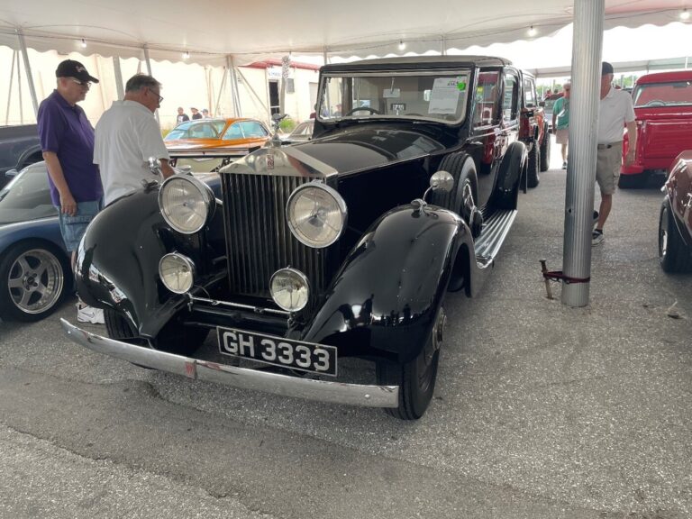 Some auction bidders looking at a vintage black Rolls Royce as car investor