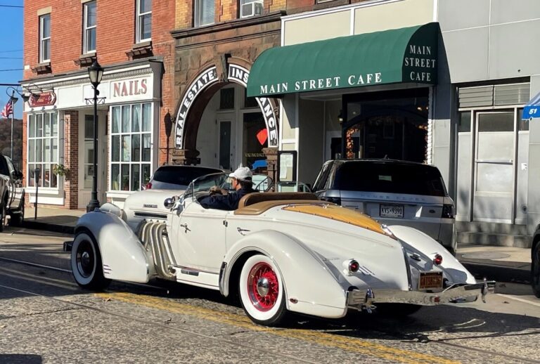 A white vintage 1940's car driving down Main Street showing the popularity of the classic car hobby