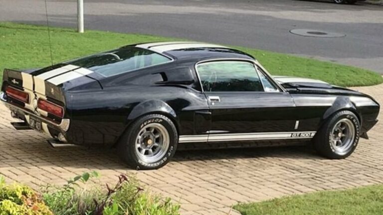 Black with white stripes Ford Shelby GT500 sitting in a driveway in front of a green lawn in mint condition shows managing classic car restoration risks