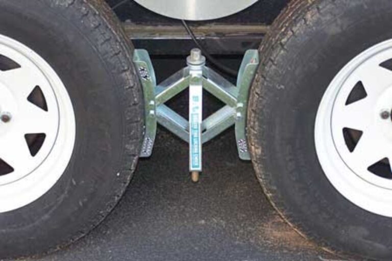 A metal wheel chock is located between the wheels to secure the car trailer.