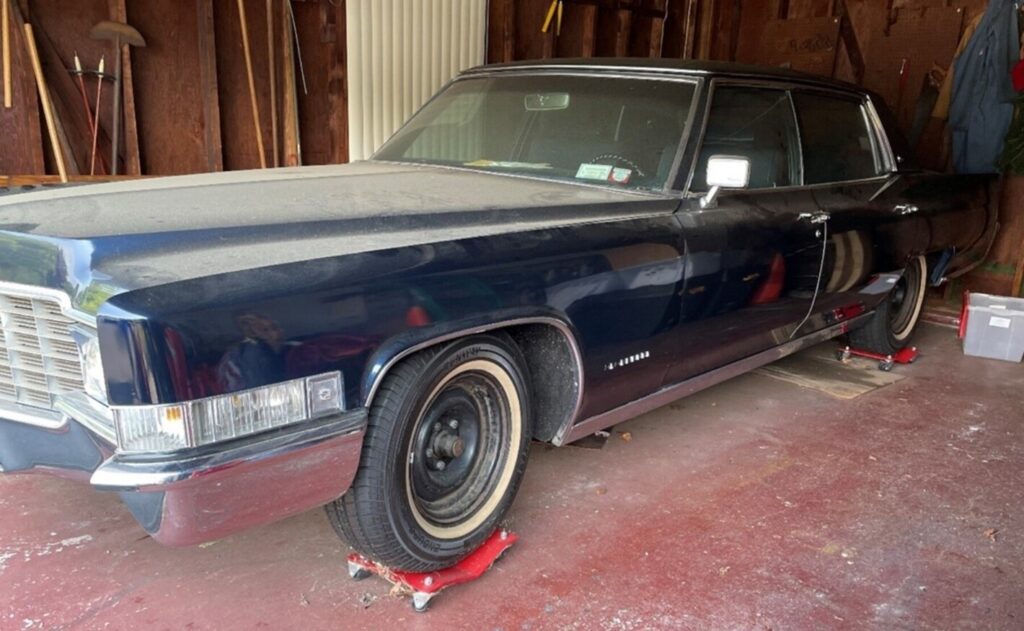 A blue 69 Cadillac in a garage with wheel dollies sitting in need of car storage preparation
