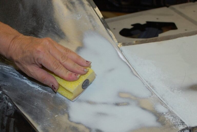 A body shop working sanding the quarter pane on a car for paint preparation to improve the restoration success rate