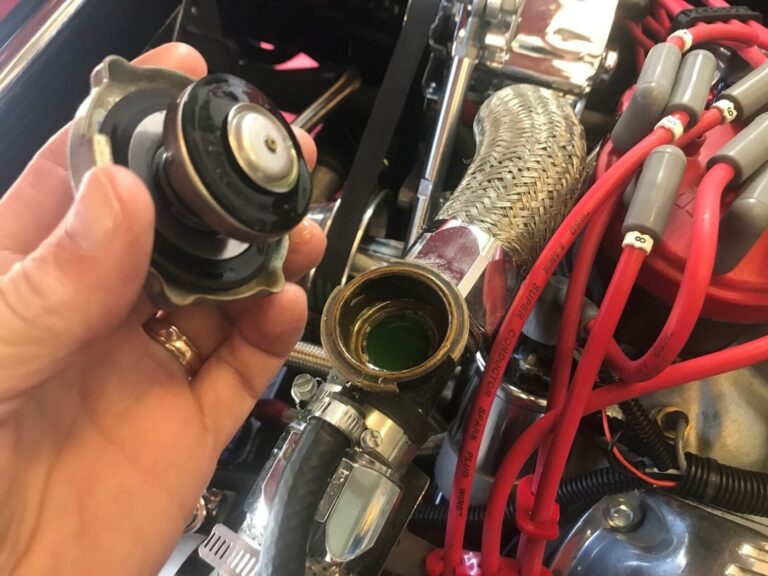 Removing the radiator cap to check the coolant as part of regular car engine maintenance
