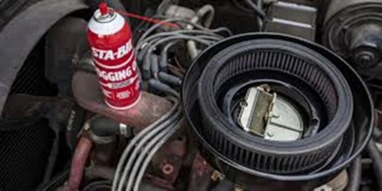 A red can of engine fogger being used to spray down the carb for car sotrage