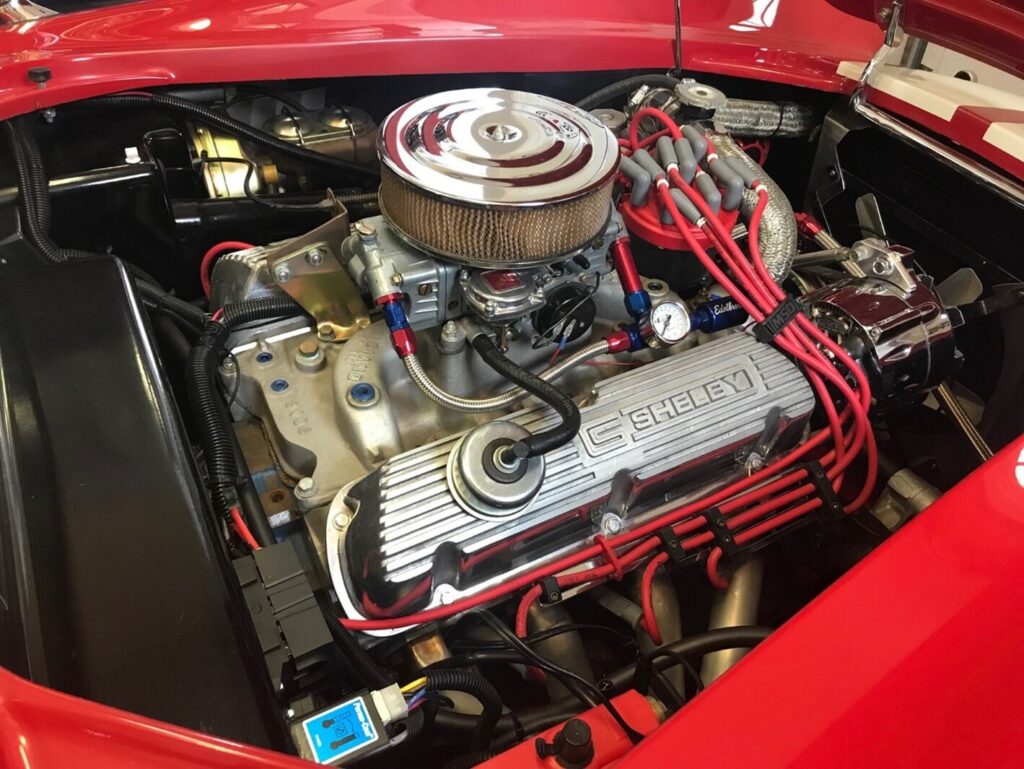 A small block Ford engine in a red Cobra with silver valve covers preparing to diagnosing common car engine noises