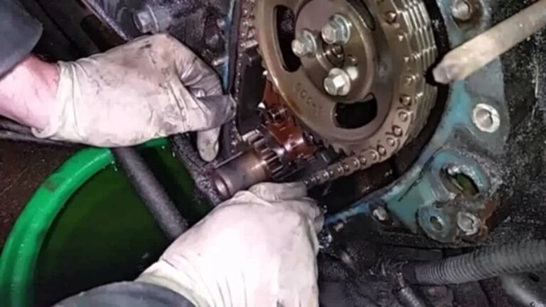 A mechanic working on a timing chain on a Pontiac engine checking for car engine noises