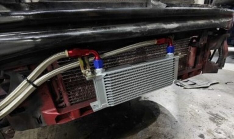 A silver oil cooler with steel braided lines mounted in front of the radiator showing the oil cooling methods
