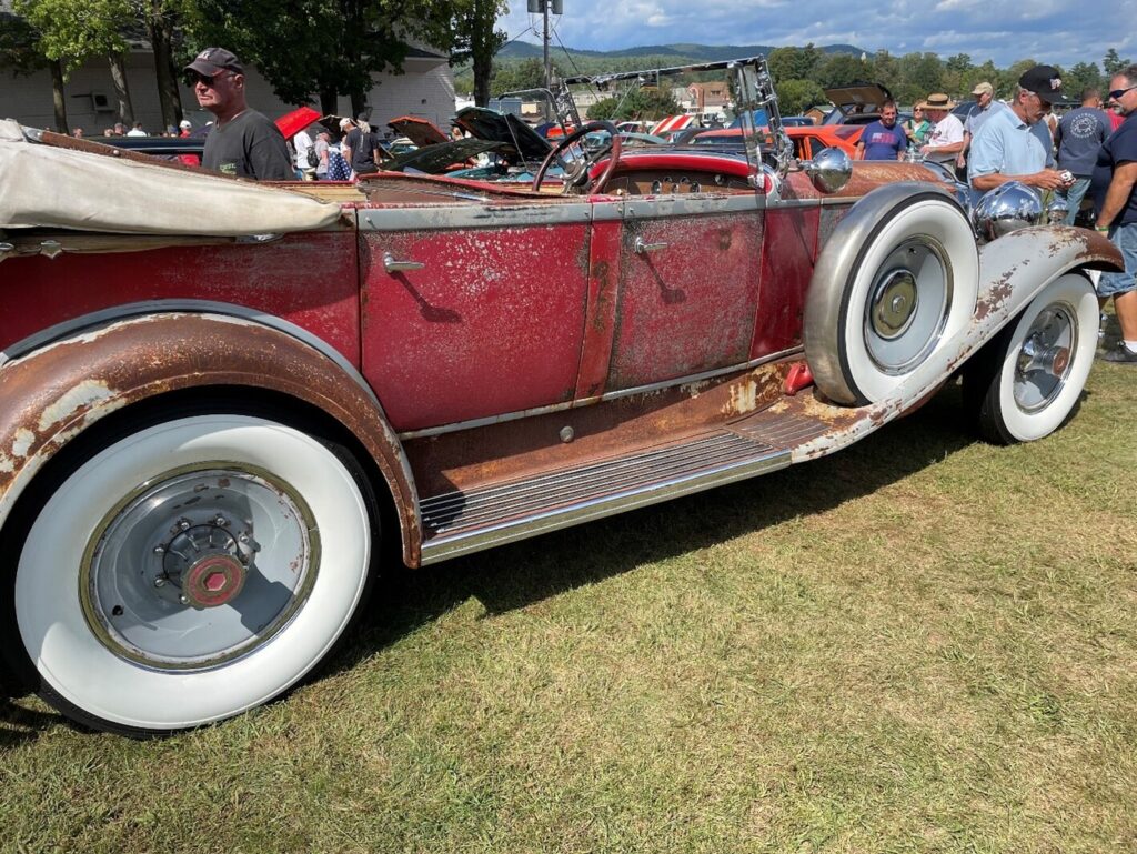 An unrestored red 4 door Rolls Royce convertible with white wall tires before making any of the common car restoration mistakes