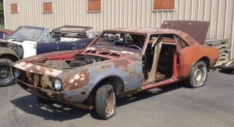 A rusty and in various colors of primer 1968 Chevy Camaro sitting on a lot next to a blue convertible avoiding common car restoration mistakes