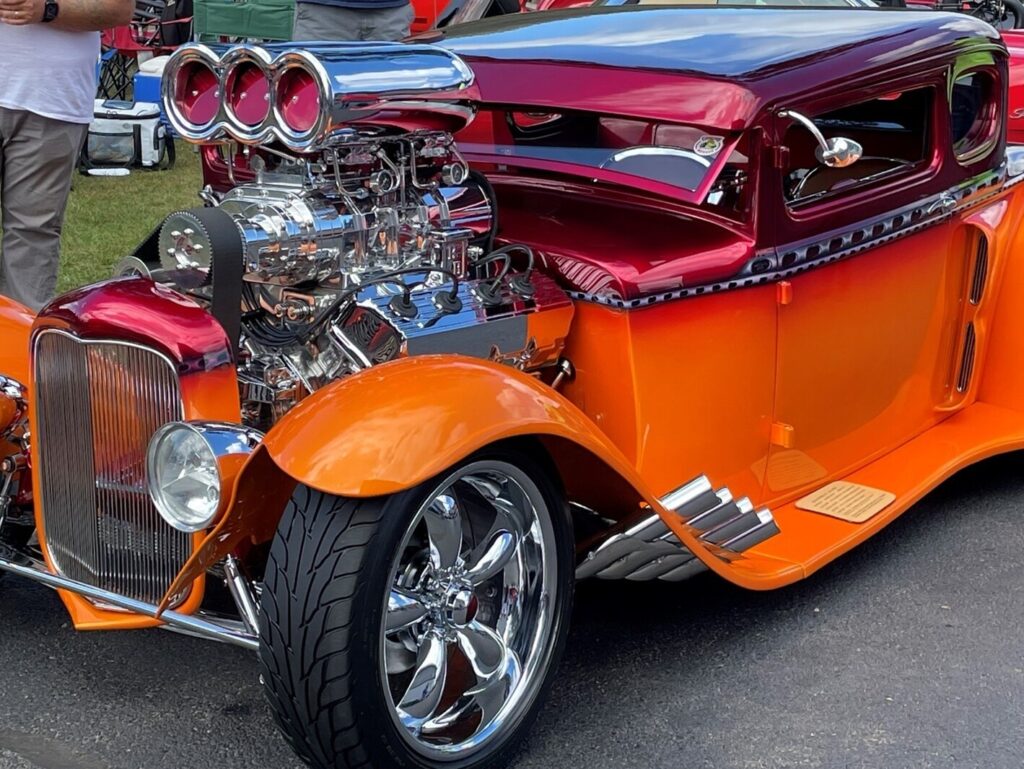 An orange and red custom 5 window Ford coupe with a chromed Hemi engine including the supercharging a car engine