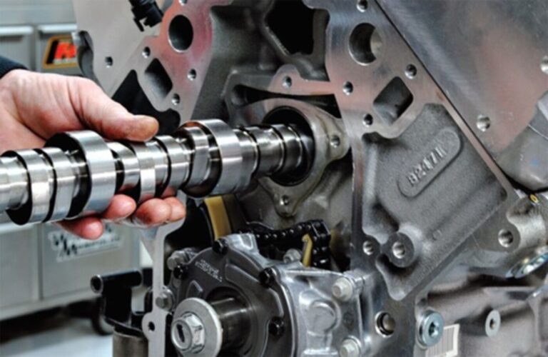 A mechanic installing a cam shaft into a silver engine as part of avoiding engine rebuilding mistakes