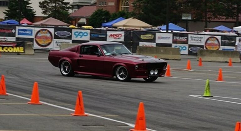 A red 69 Ford Mustang turning on aa road racecourse noting the importance of the car's weight distribution.