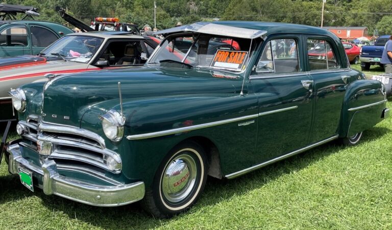 A green 4 door Dodge parked in a field with a For Sale sign on the front window to help avoid classic car fraud when buying is knowledge