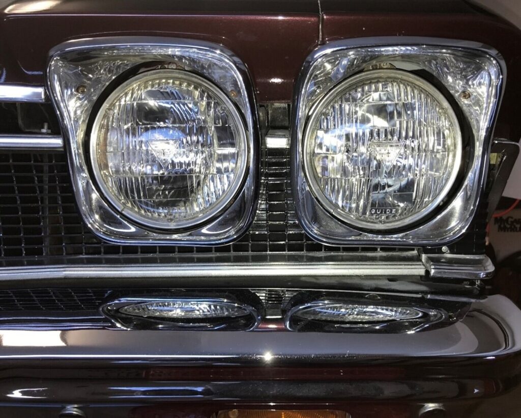 Front left car headlight on a maroon 1968 Chevy Chevelle with chrome bezels