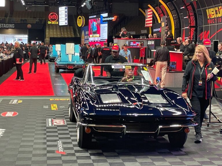 A group of 3 blue Chevy Corvettes passing across the auction block with people pushing the cars as buyers know the best time to buy a classic car