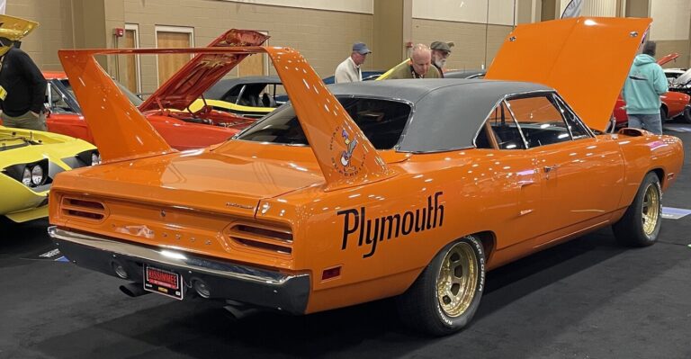An orange Plymouth Superbird in front of other classic cars