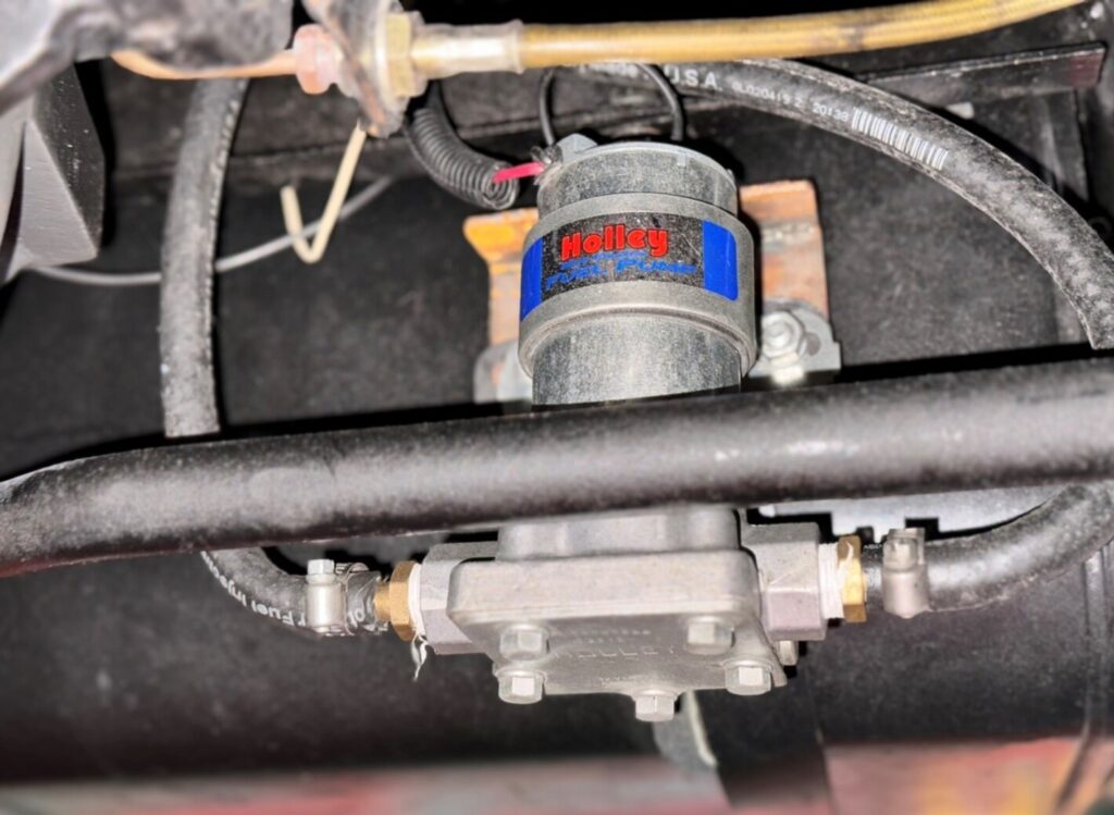 A silver in-line Holley electric fuel pump installed next to the fuel tank