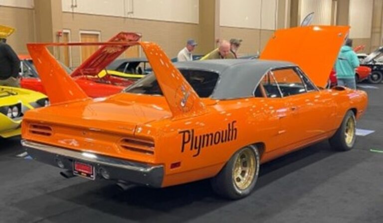 An orange and black Plymouth Superbird on display at a car auction