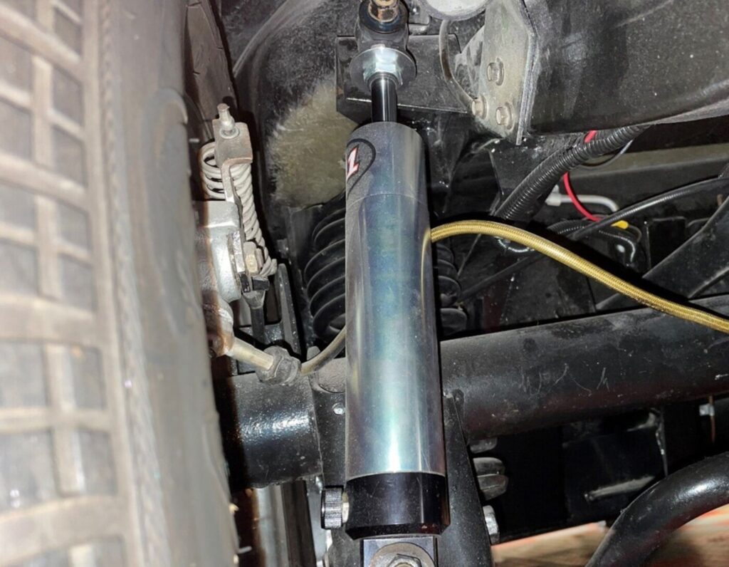 A silver QU adjustable rear shock absorber damping rate installed on a car