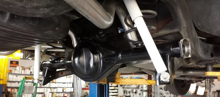 A black Ford 9-inch rear end being test fit into a Chevy car with white shock absorbers