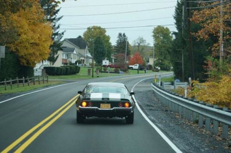 A 70 Chevy Camaro with an automatic transmission on a two-lane highway in a rural rural area