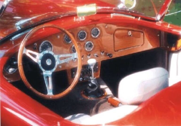 A red Shelby Cobra with white seats and an automatic transmission