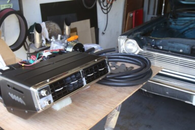 An aftermarket air conditioning system on a work bench prior to being installed in a black Ford sedan