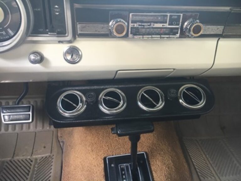 A black aftermarket air conditioning diffuser installed under the dash of a Ford car