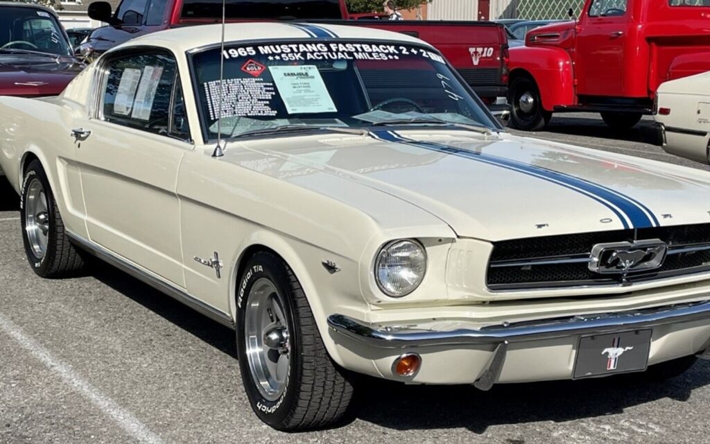 A white with blue stripes 1965 Ford Mustang with the documentation to prove it is a numbers matching classic car