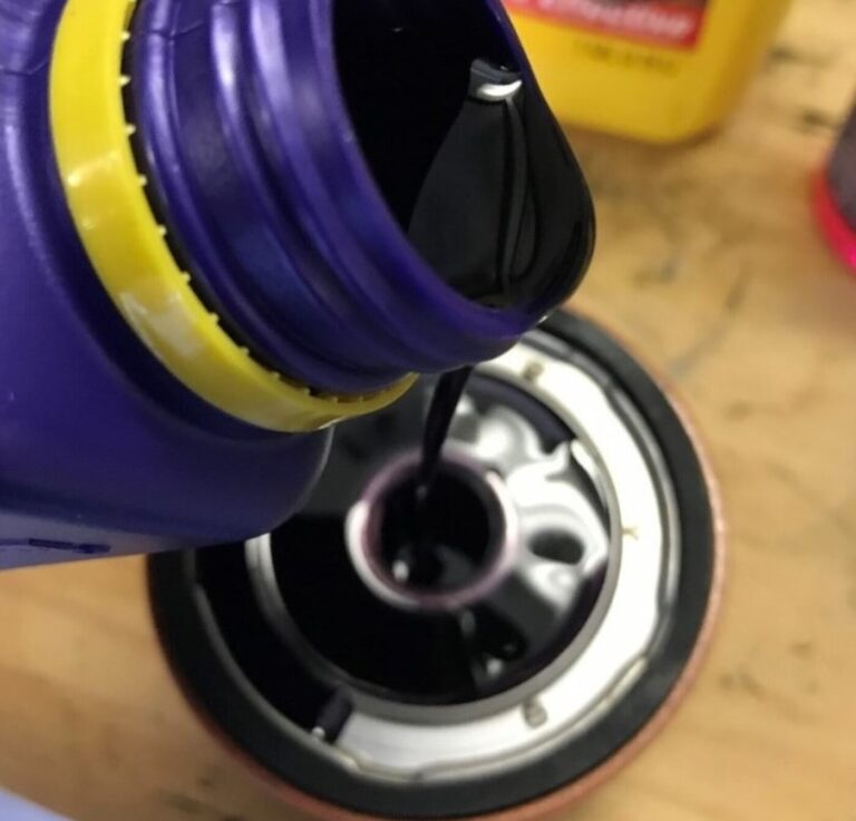 Pouring neww oil into a new oil filter in preparation for driving in extreme heat