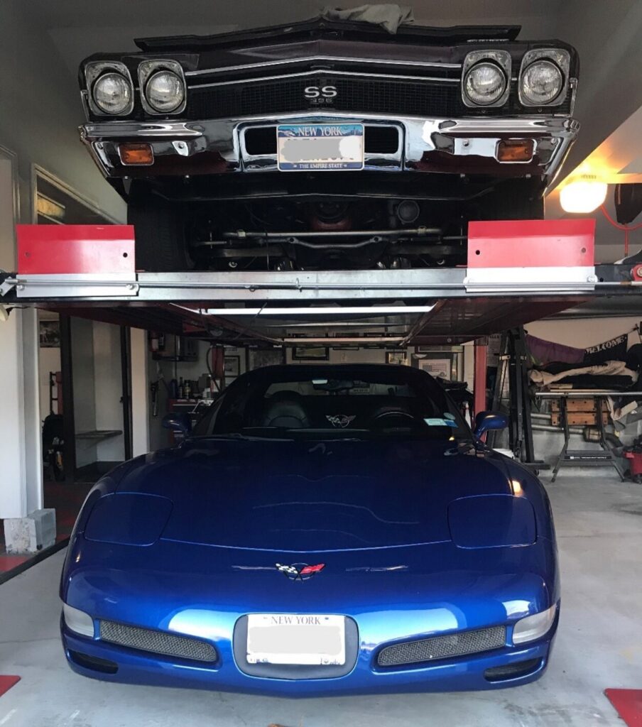 2 cars om a lift with a 68 Chevelle on top of a 2002 blue Corvette showing how to store more that one car in a garage