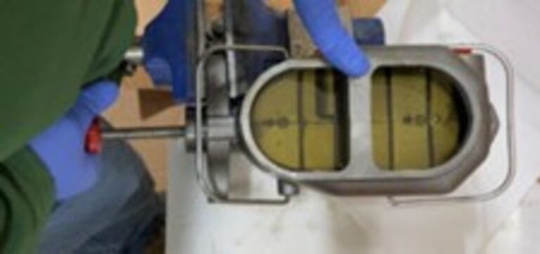 A mechanic with blue gloves pressing the master cylinder piston to bleed air from the master cylinder