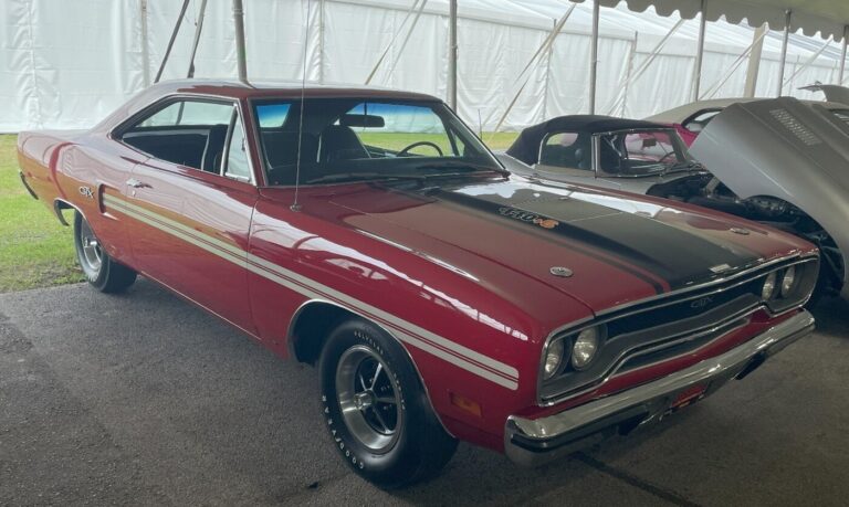 A red/black Plymouth GTX at a car auction as an example of an American muscle cars