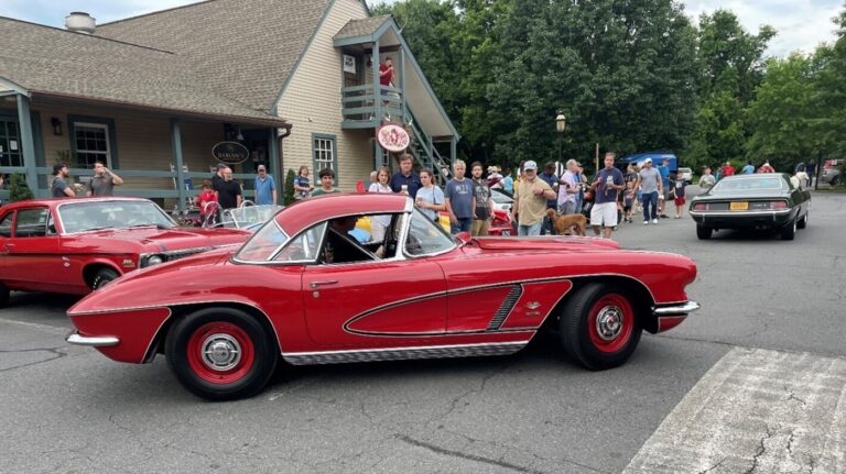 A red Chevy Corvette driving thru a car show as part of the vintage car hobby