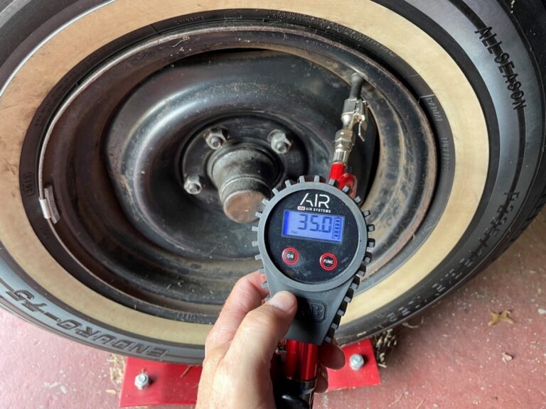 A modern car repair tool of a digital air pressure gauge being used to check a vintage tire prressure