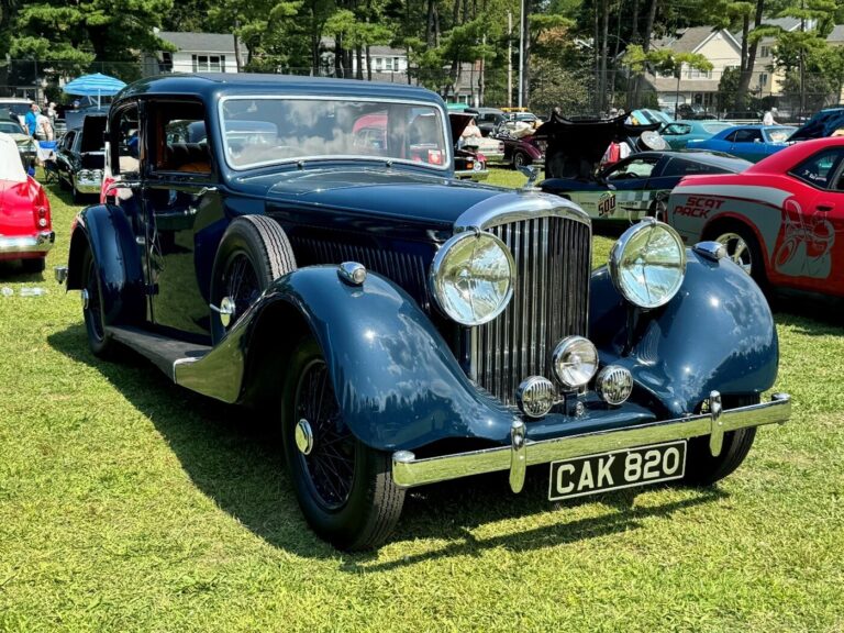 A vintage black Rolls Royce parked on the grass at a car show after a concours restoration