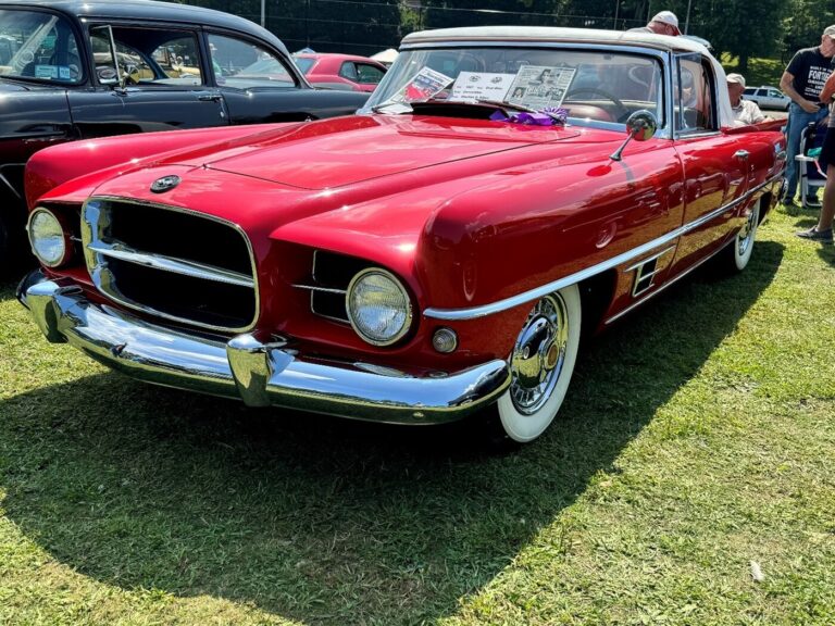 A red Dual Ghia parked on the grass at a car show after a concours restoration