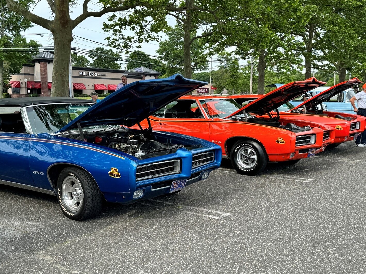 A blue Pontiac GTO Judge convertible next to 2 red Pontiac GTO Judges at a car show discussing the greatest classic car misconceptions ever