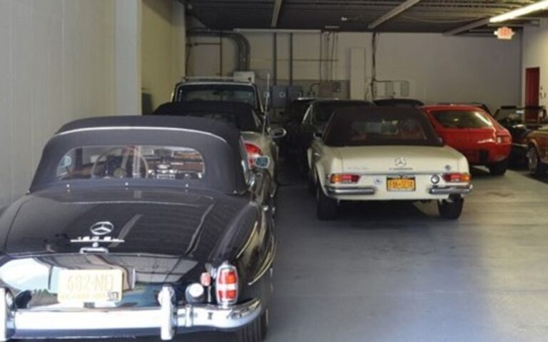 Black and white Mercedes Benz SL convertibles along with a red Porsche 928 parked inside a storage facility to comply with classic car insurance requirements