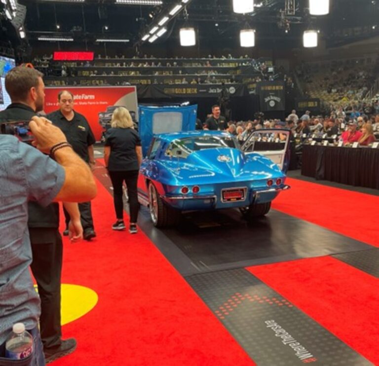A blue 1965 Corvette Coupe custom at a car auction as people watch to address classic car misconceptions