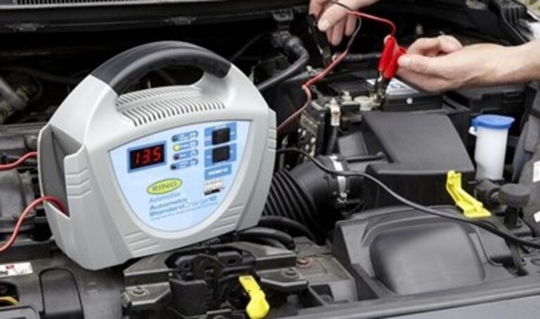A mechanic using a battery tender as part of the vintage car winterizing process