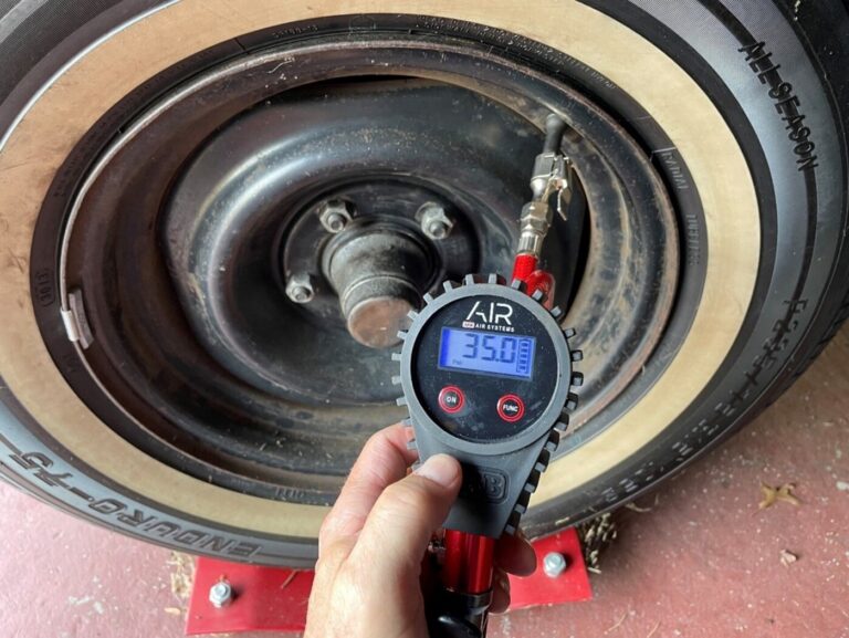 A mechanic checking the tire pressure (at 35 lbs) with a digital tire gauge as part of the vintage car winterizing process